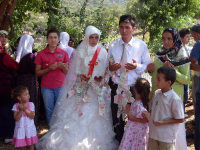 Newly married couple from Turkey. The bride wears a long white gown and red sash.