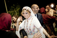 Palestinian bride dances at her wedding with elaborate headdress made of gold coins.