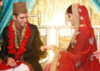 Indian Muslim couple. The groom in traditional headgear and bride in red sari.