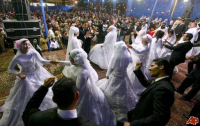 Mass wedding in Egypt with brides and grooms dancing their cares away.